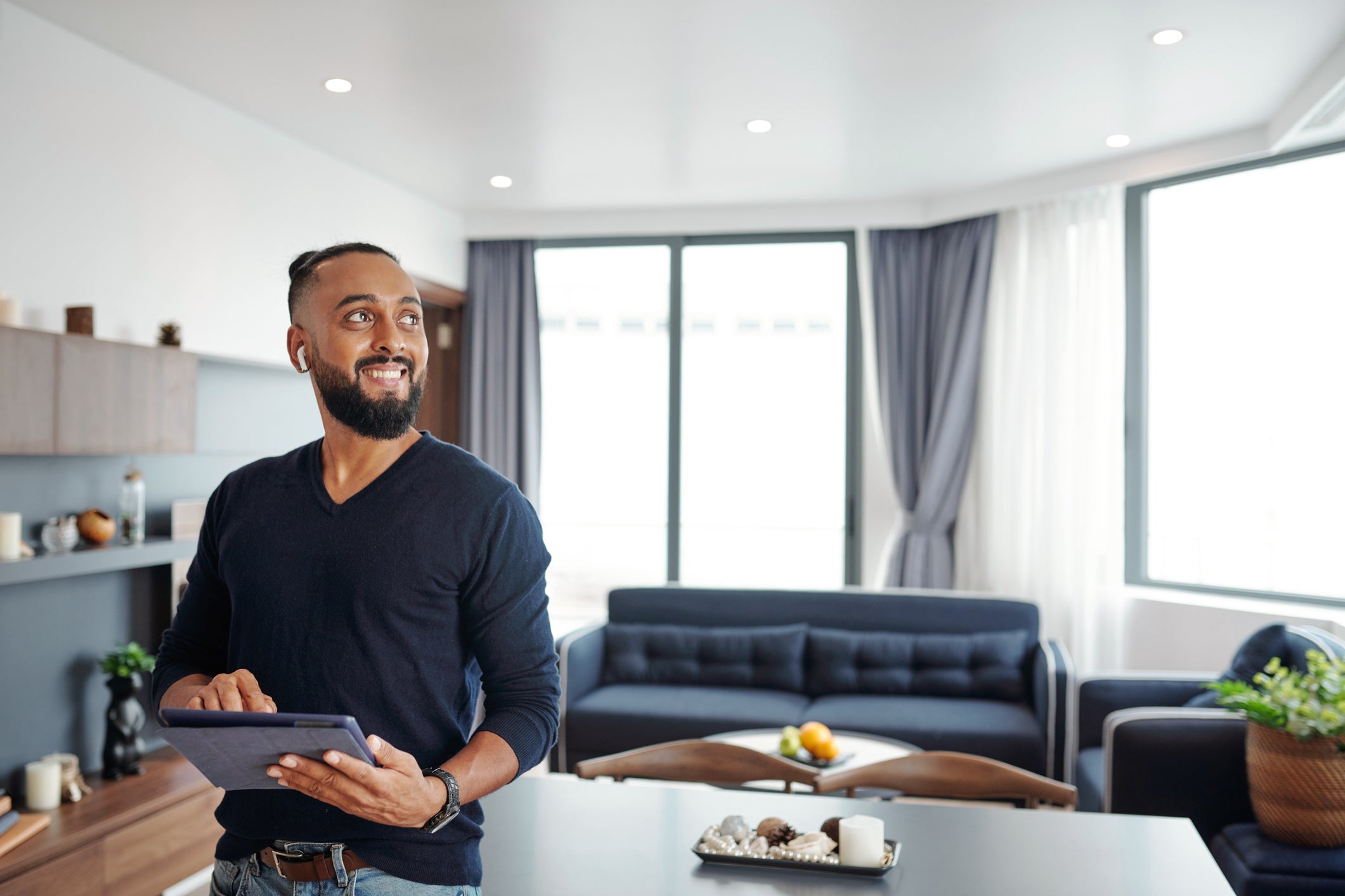 A man stands in the living room, holding a tablet and engaging with its screen in Lynnwood, WA